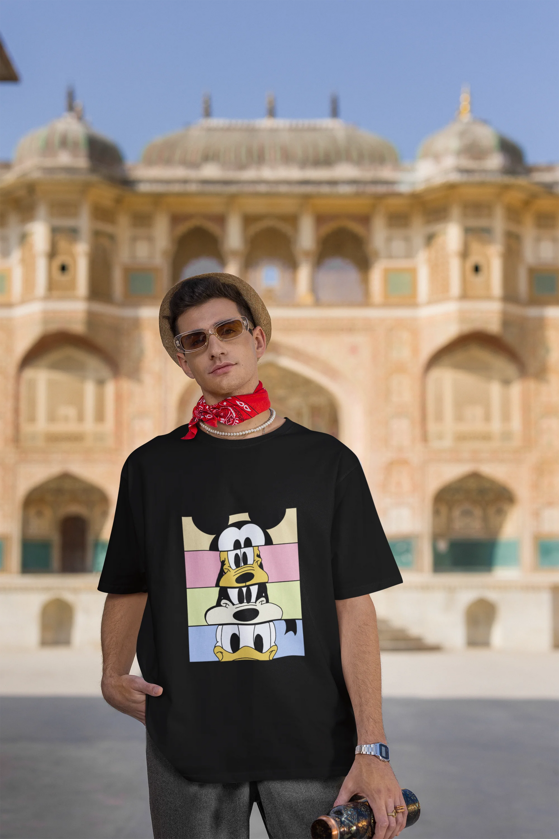 Third image of male Model showcasing black oversized t-shirt inspired by Mickey Mouse Clubhouse characters: Mickey Mouse, Donald Duck, Goofy, and Minnie Mouse