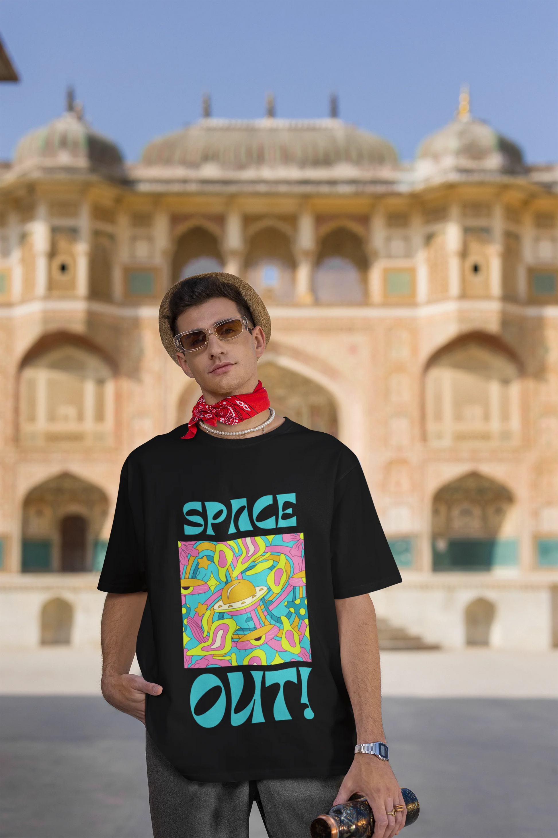 Third image of male model wearing an black oversized "Spaced Out" t-shirt featuring a vibrant color mashup design that evokes a sense of space exploration, playful aliens, and distant galaxies.