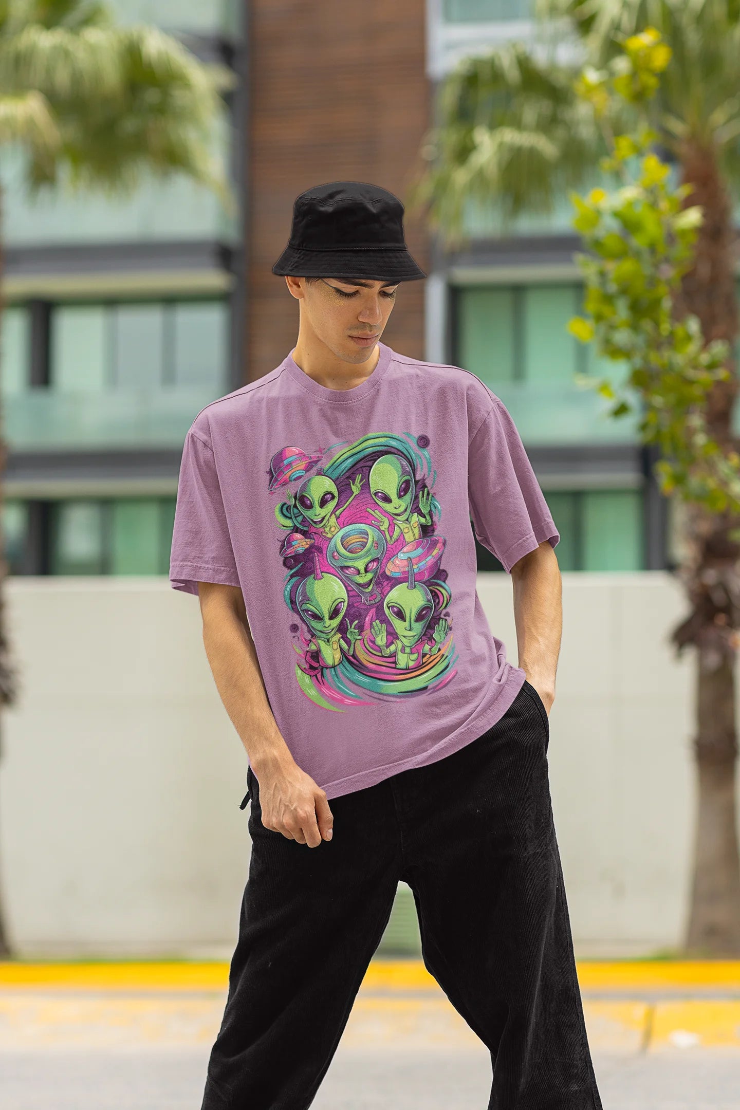 Front side view of a male model wearing a dirty purple oversized t-shirt with a psychedelic design featuring green aliens and spaceships, perfect for a hippie, trance, or groovy style.