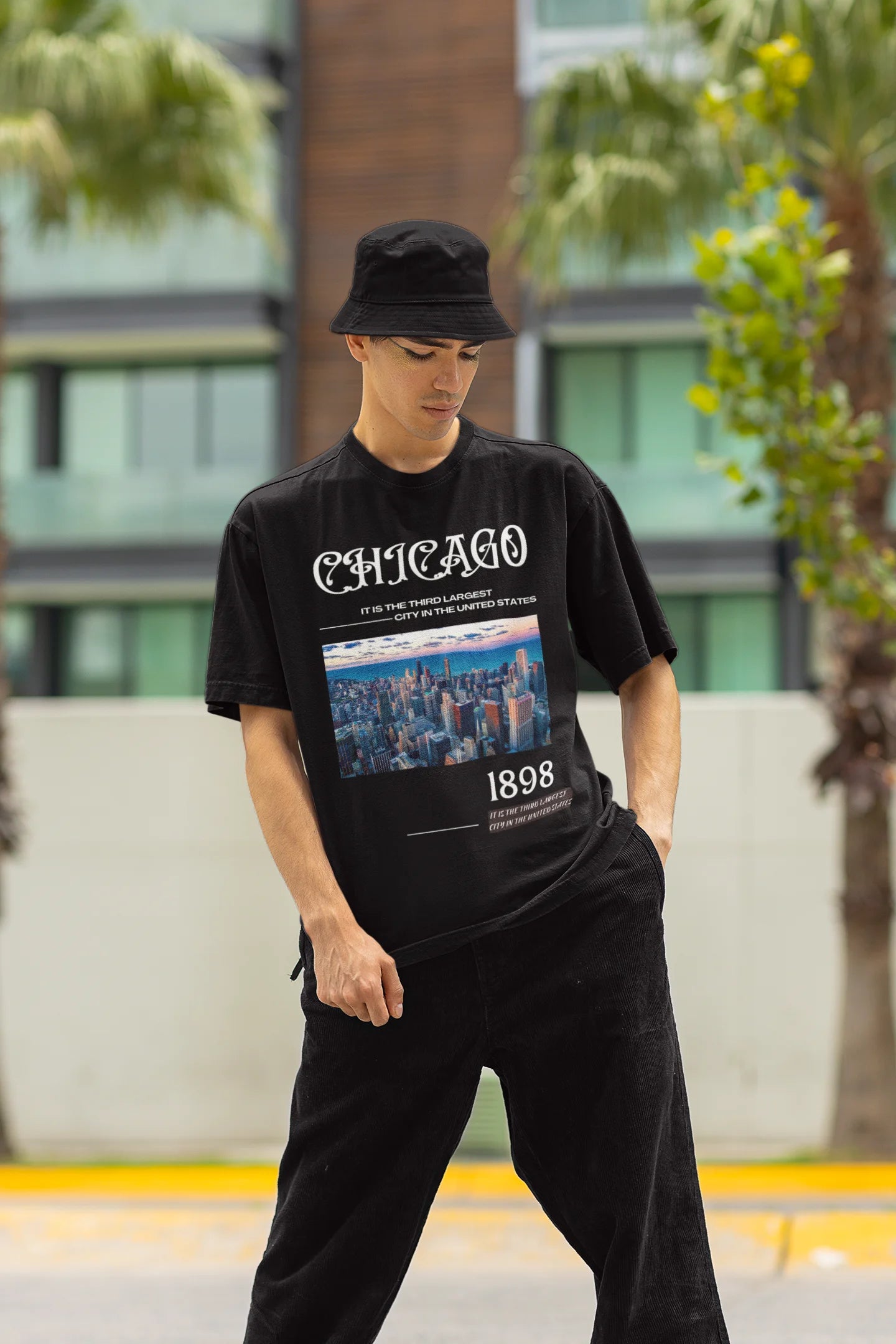 Front view of male model wearing a black oversized t-shirt with a Chicago skyline design, offering a relaxed urban aesthetic.