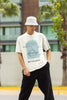 Front view of a male model wearing a off-white oversized t-shirt with a beautiful outline of the sun setting into the sea, offering a serene and coastal aesthetic.