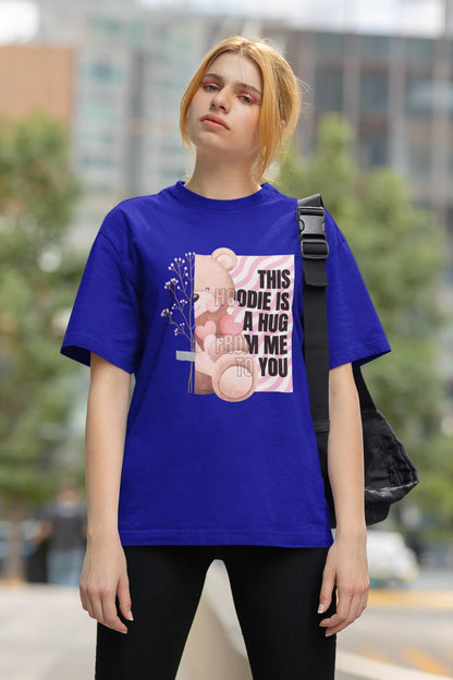 Third front view of a female model wearing an royal blue oversized t-shirt with a heartwarming design of a teddy bear offering a hug, offering a comforting and relaxing aesthetic.