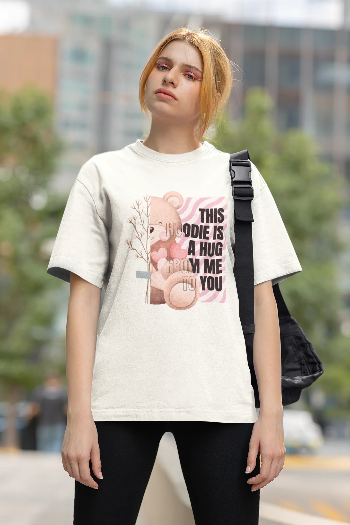 Second front view of a female model wearing an off-white oversized t-shirt with a heartwarming design of a teddy bear offering a hug, offering a comforting and relaxing aesthetic.