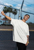 Front view of male model wearing an off-white oversized t-shirt featuring a thought-provoking design of a golden lock shaped like an insect. Ideal for those who love symbolic clothing and unique conversation starters.