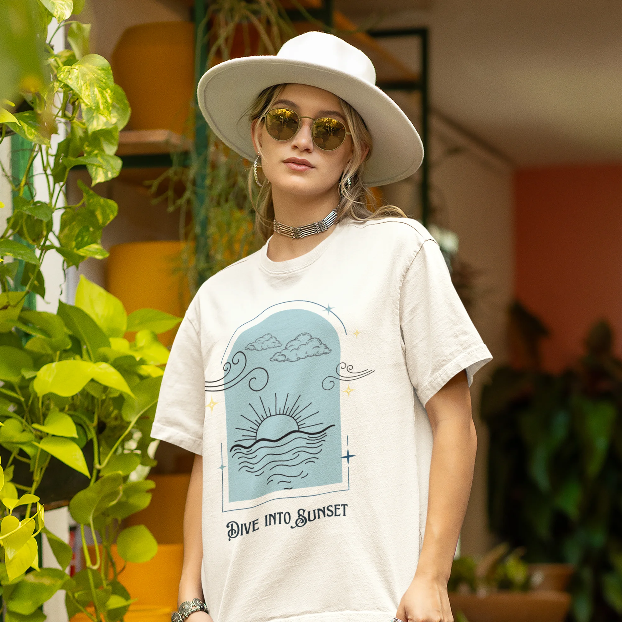 Front view of a female model wearing a off-white oversized t-shirt with a beautiful outline of the sun setting into the sea, offering a serene and coastal aesthetic.