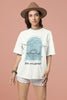 Second front view of a female model wearing a off-white oversized t-shirt with a beautiful outline of the sun setting into the sea, offering a serene and coastal aesthetic.