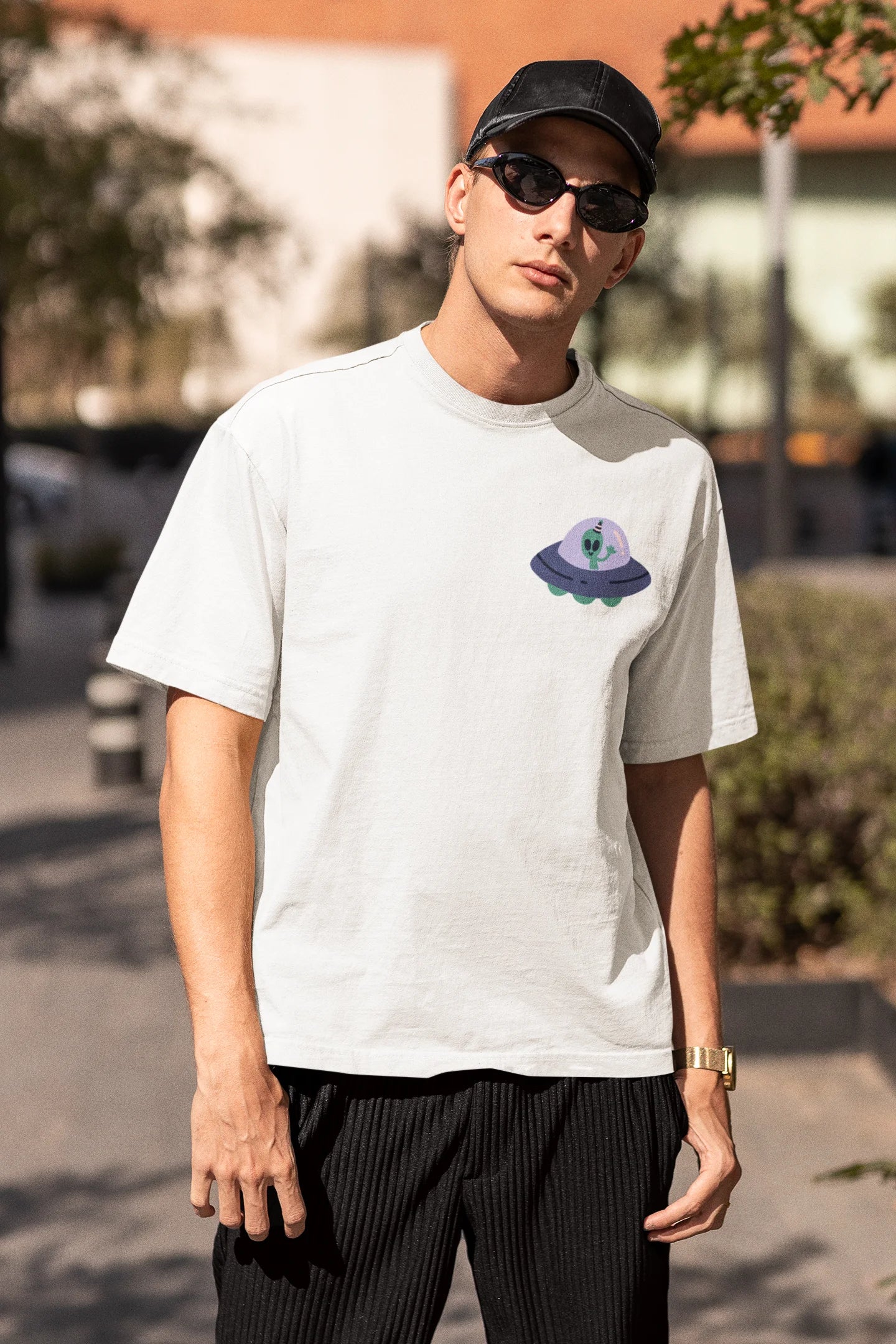 Third front view of a male model wearing a off-white oversized t-shirt featuring a fun "Alienated" design with elements of spaceships, UFOs, and a hint of extraterrestrial life.