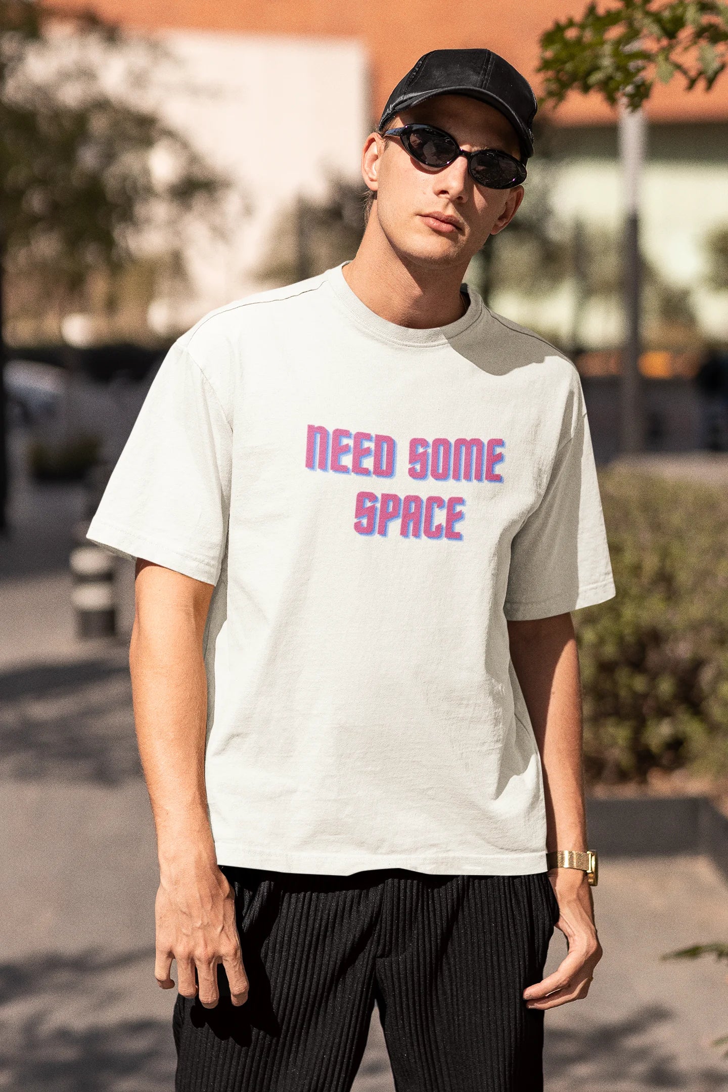 Third front view image of a male model wearing a white oversized t-shirt with a bold graphic that reads "Need Some Space" on the front. The design incorporates subtle hints of the Milky Way galaxy and the solar system on the back.