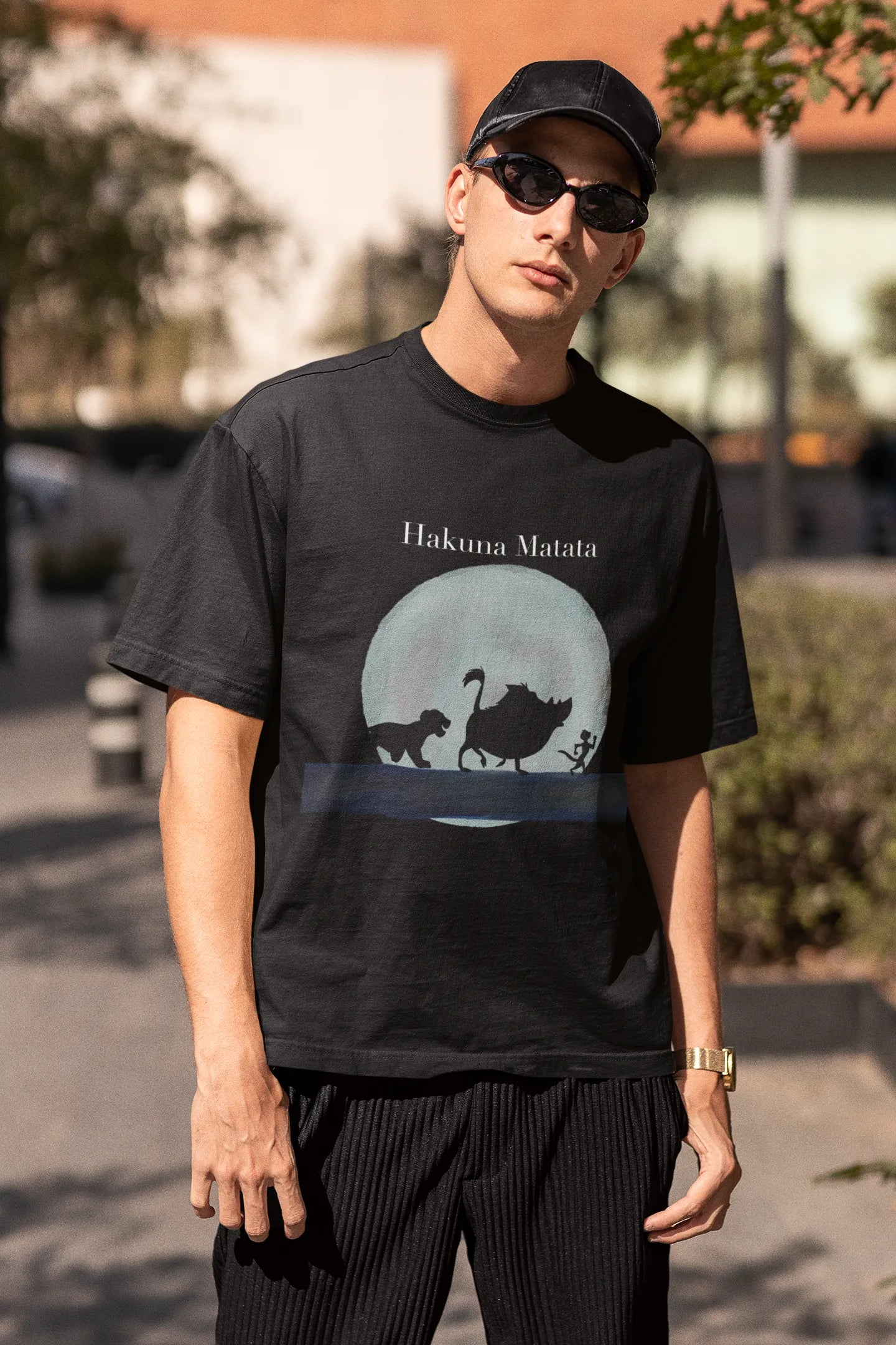 Third image of male model showcasing black oversized t-shirts inspired by Hakuna Matata from Disney's Lion King, featuring Pumbaa, Simba and other iconic characters.