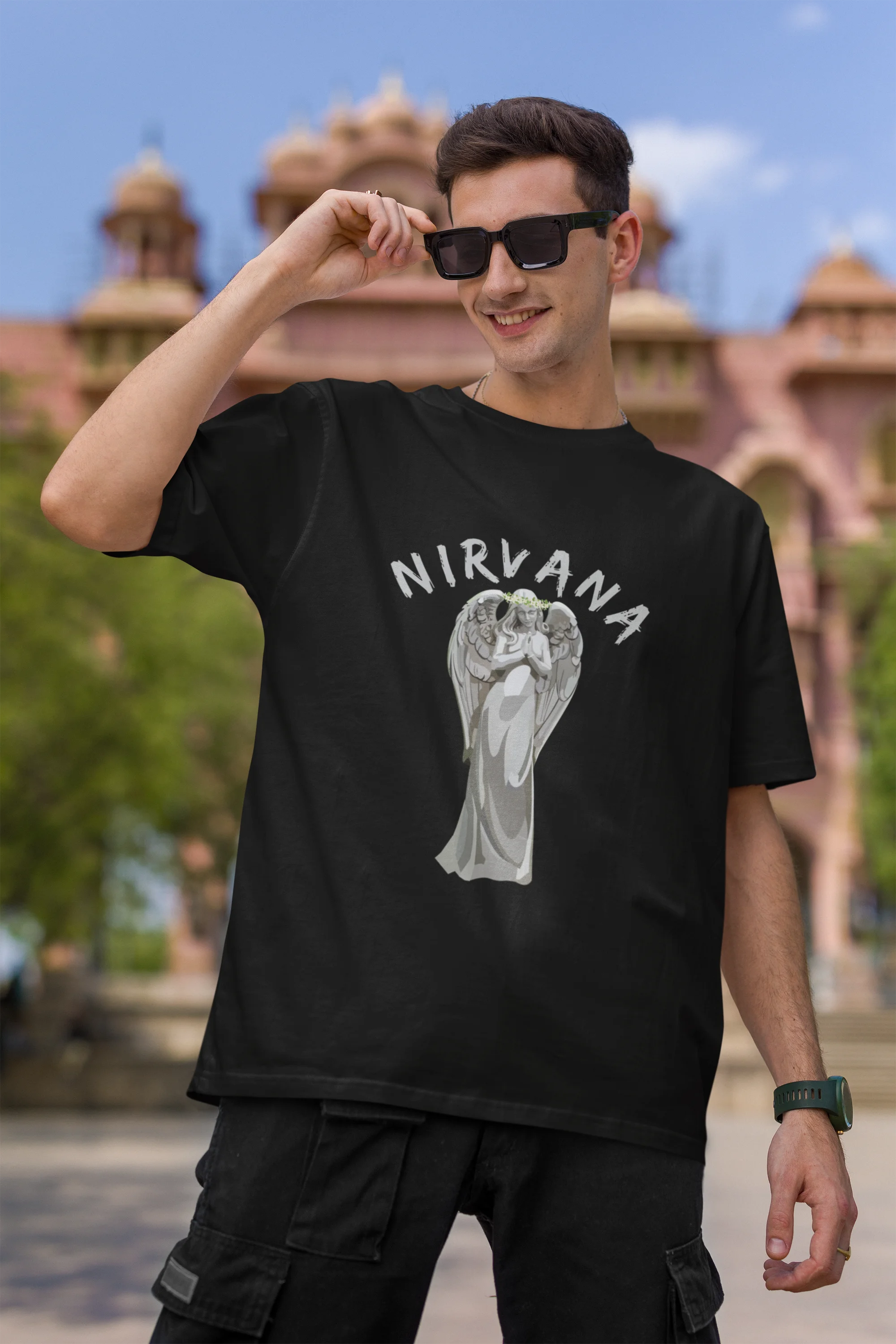 Second front image of male model wearing a black oversized t-shirt featuring a design of a winged angel with the text "Nirvana" above it. Ideal for fans of Nirvana and those who love grunge aesthetics.