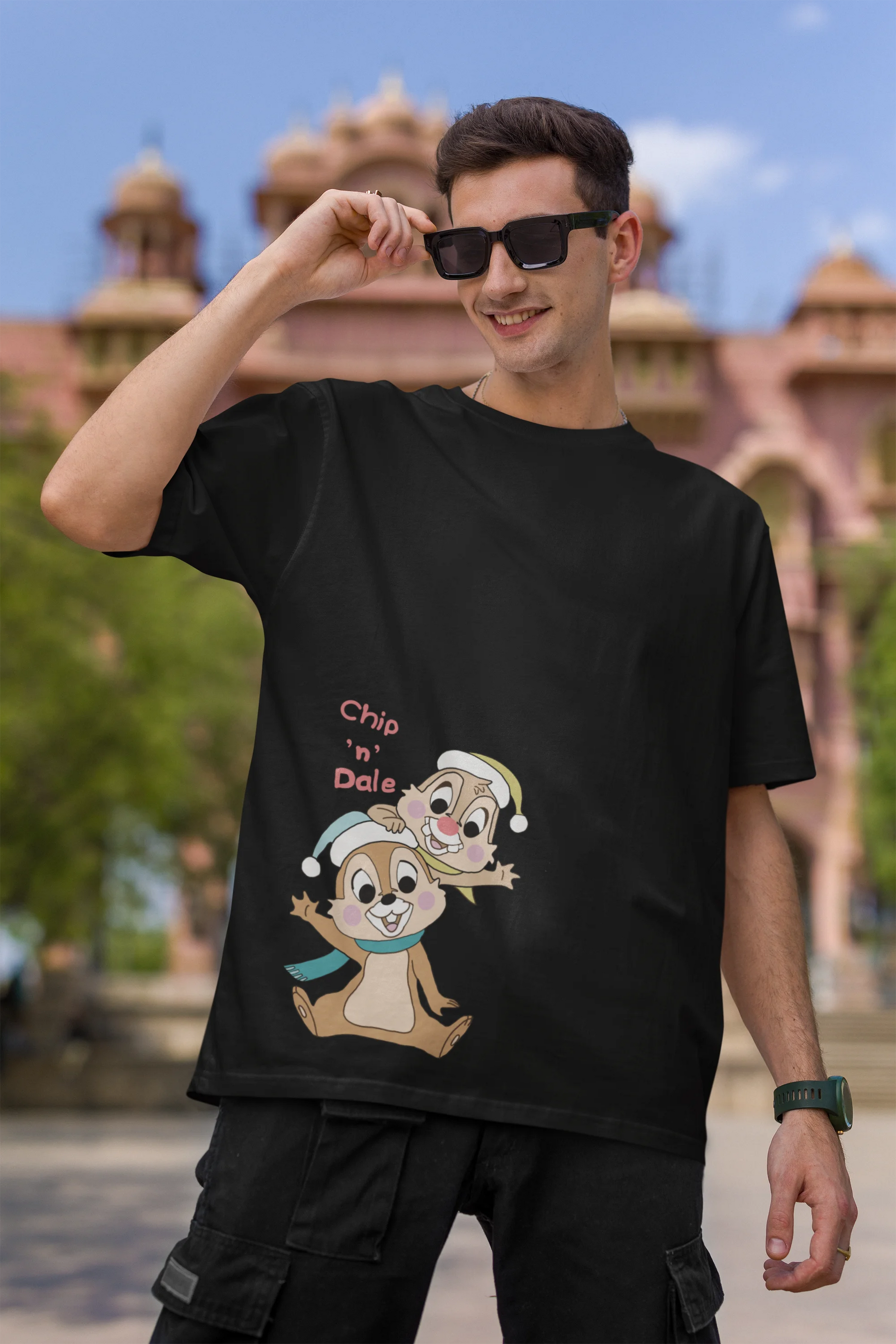 First image of male model wearing black oversized tee with a Disney's Chip and Dale design, featuring the adorable duo in a playful scene.