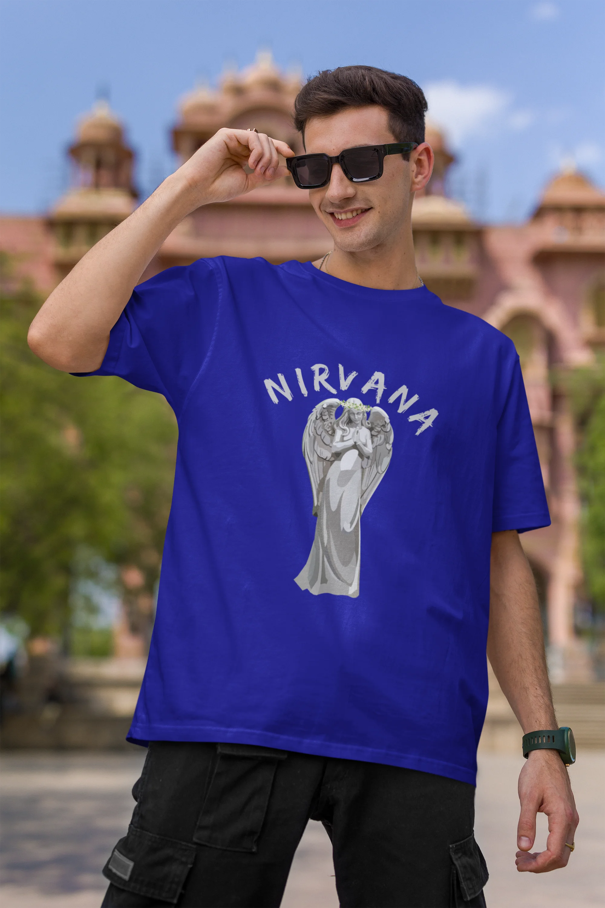 First front image of male model wearing a royal blue oversized t-shirt featuring a design of a winged angel with the text "Nirvana" above it. Ideal for fans of Nirvana and those who love grunge aesthetics.