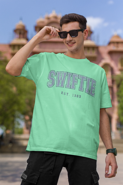First image of man wearing mint green Oversize T-shirt featuring Swiftie design, taylor's version