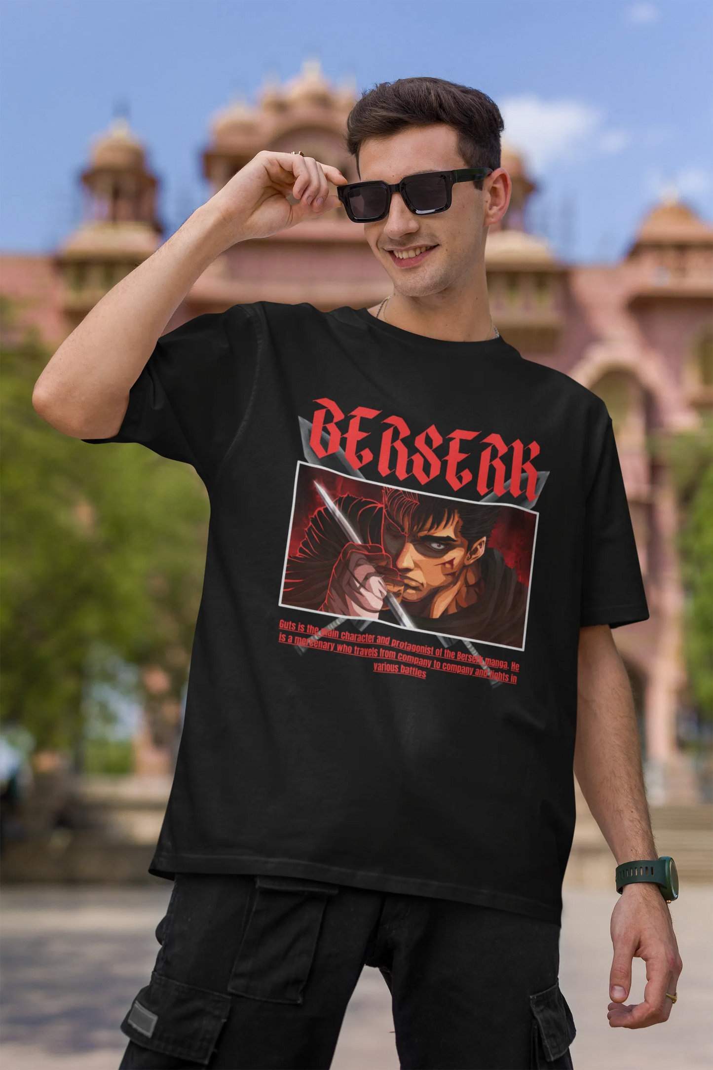 First front view of a male model wearing an black oversized t-shirt featuring Guts from the Berserk anime with the text "Berserk" across the design.