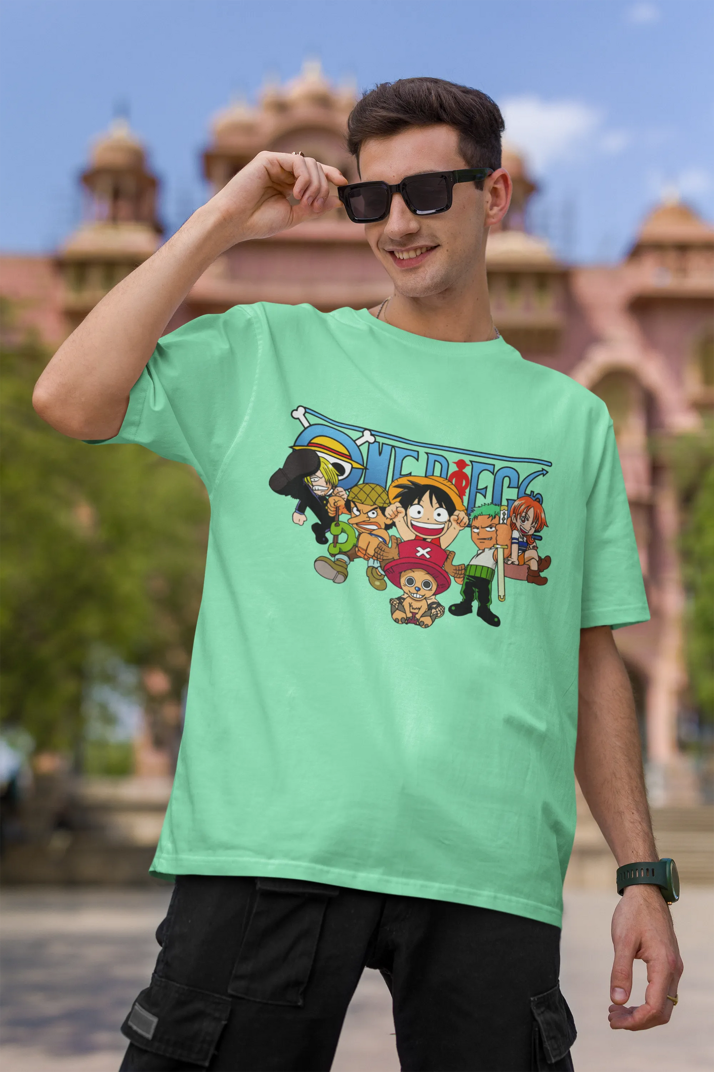 First front view of a male model wearing a mint green oversized t-shirt featuring chibi versions of the Straw Hat Crew from the One Piece anime.