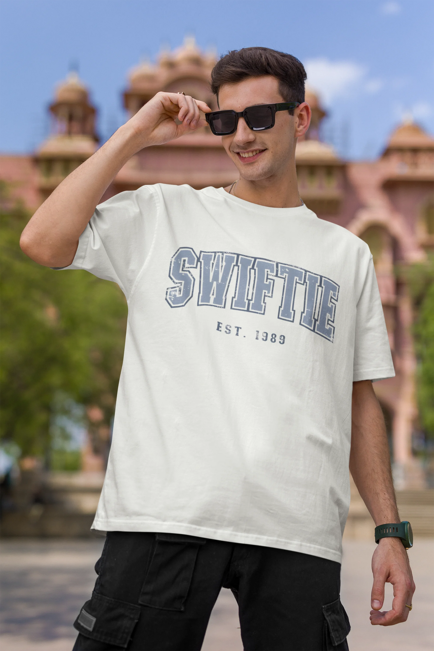 First image of man wearing off white Oversize T-shirt featuring Swiftie design, taylor's version