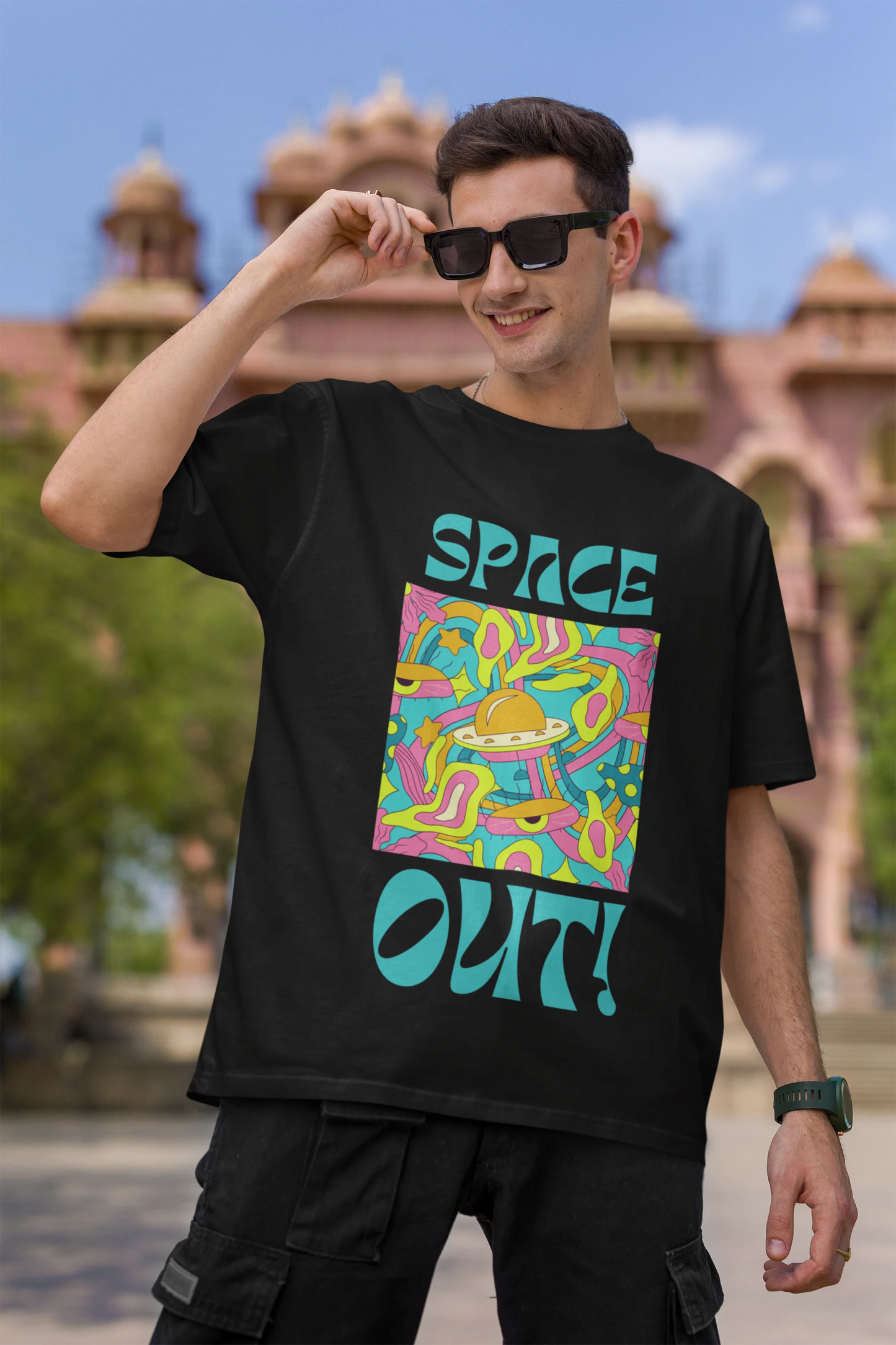 Second image of male model wearing an black oversized "Spaced Out" t-shirt featuring a vibrant color mashup design that evokes a sense of space exploration, playful aliens, and distant galaxies.