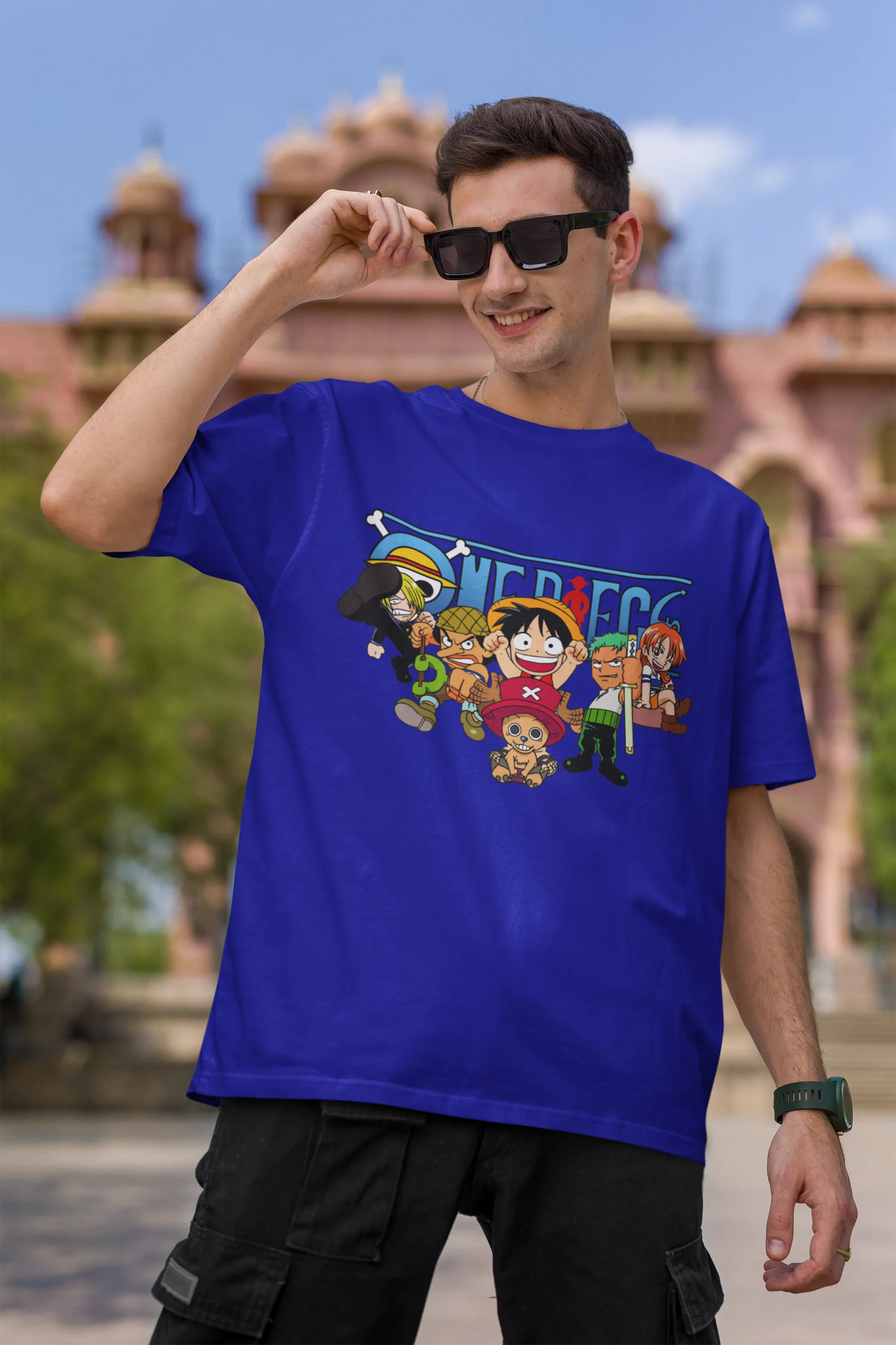 First front view of a male model wearing a royal blue oversized t-shirt featuring chibi versions of the Straw Hat Crew from the One Piece anime.