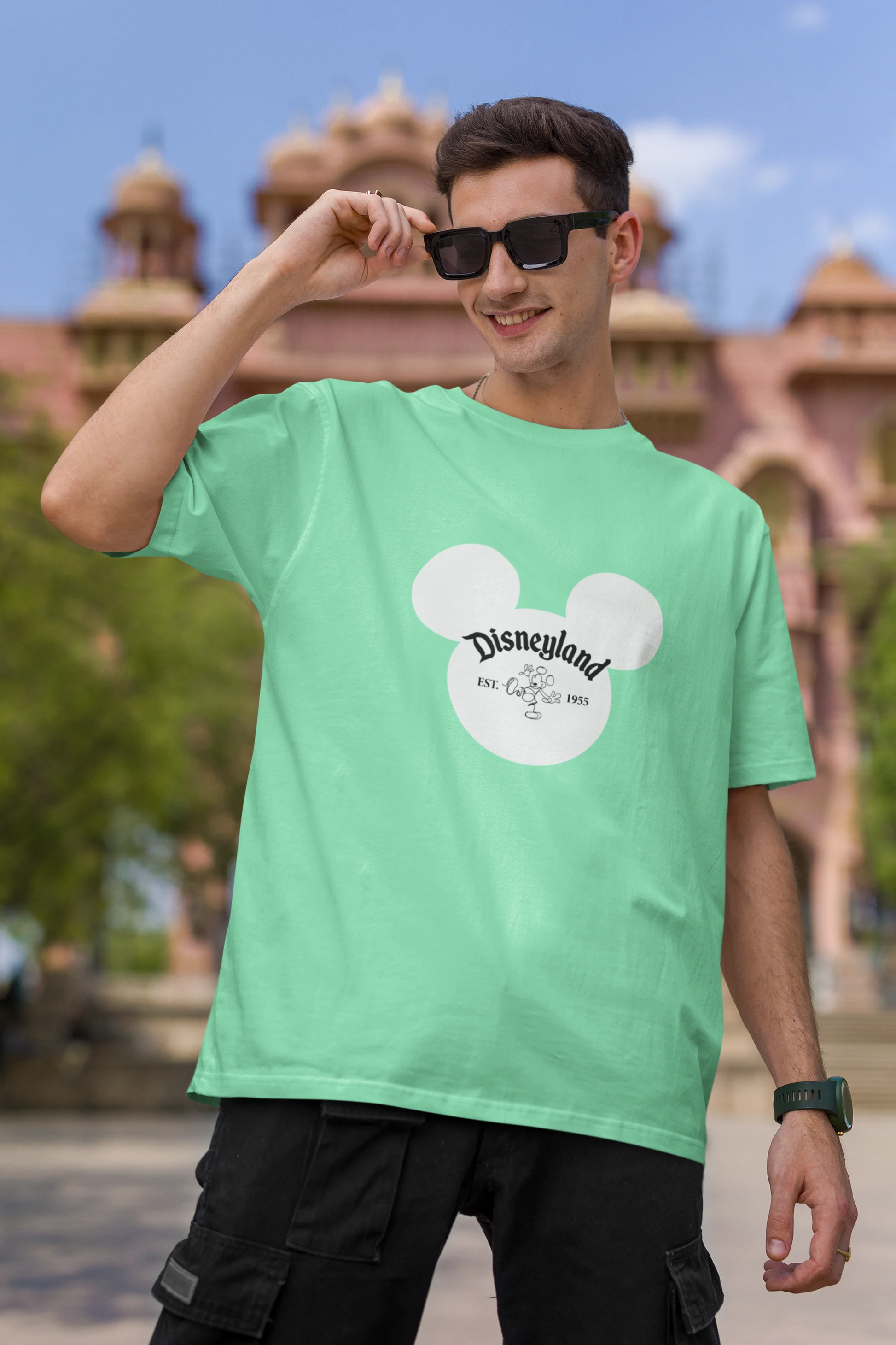 First image of male model wearing a mint green oversized Disney collection t-shirt featuring a classic Disneyland design.