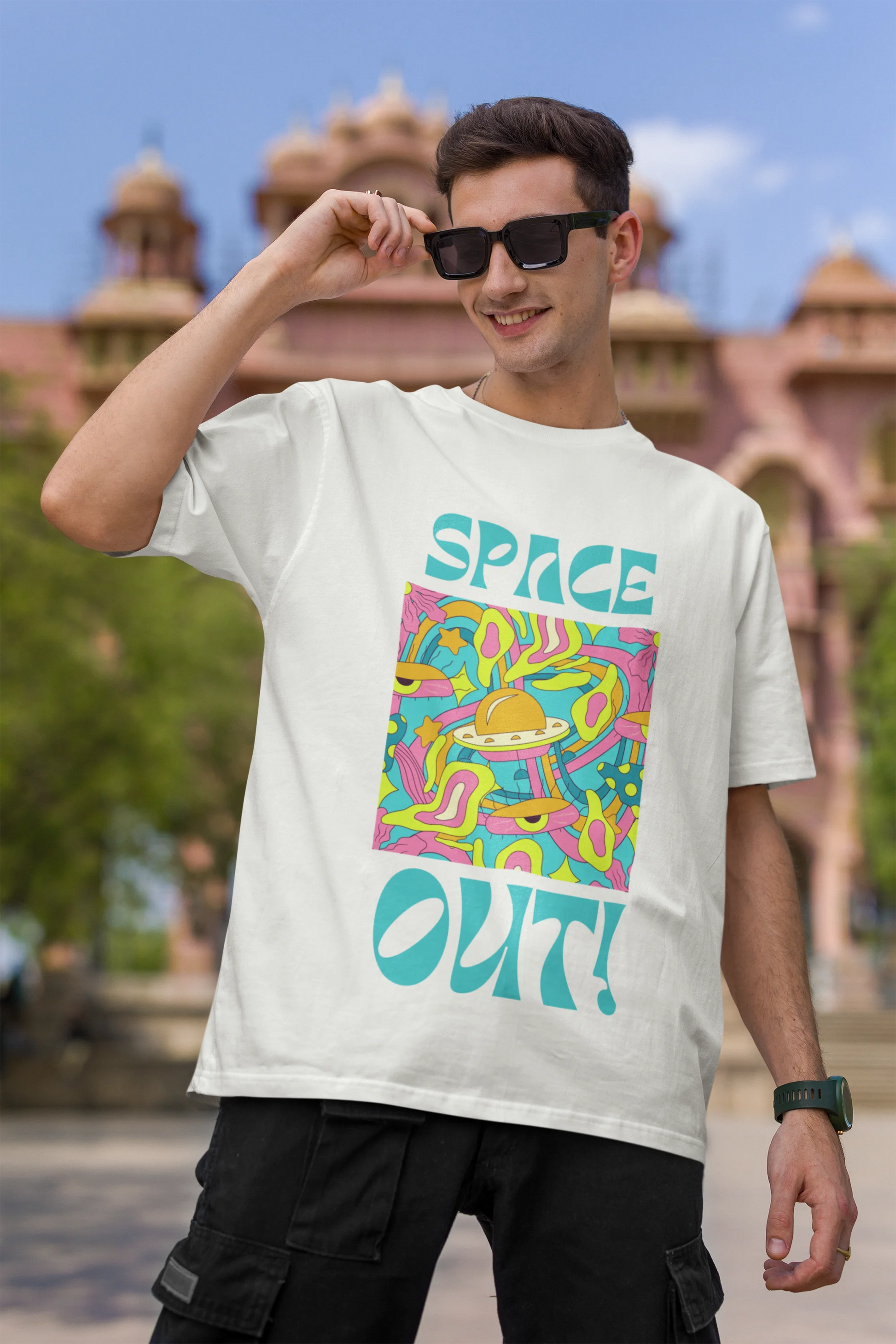 First image of male model wearing an off white oversized "Spaced Out" t-shirt featuring a vibrant color mashup design that evokes a sense of space exploration, playful aliens, and distant galaxies.