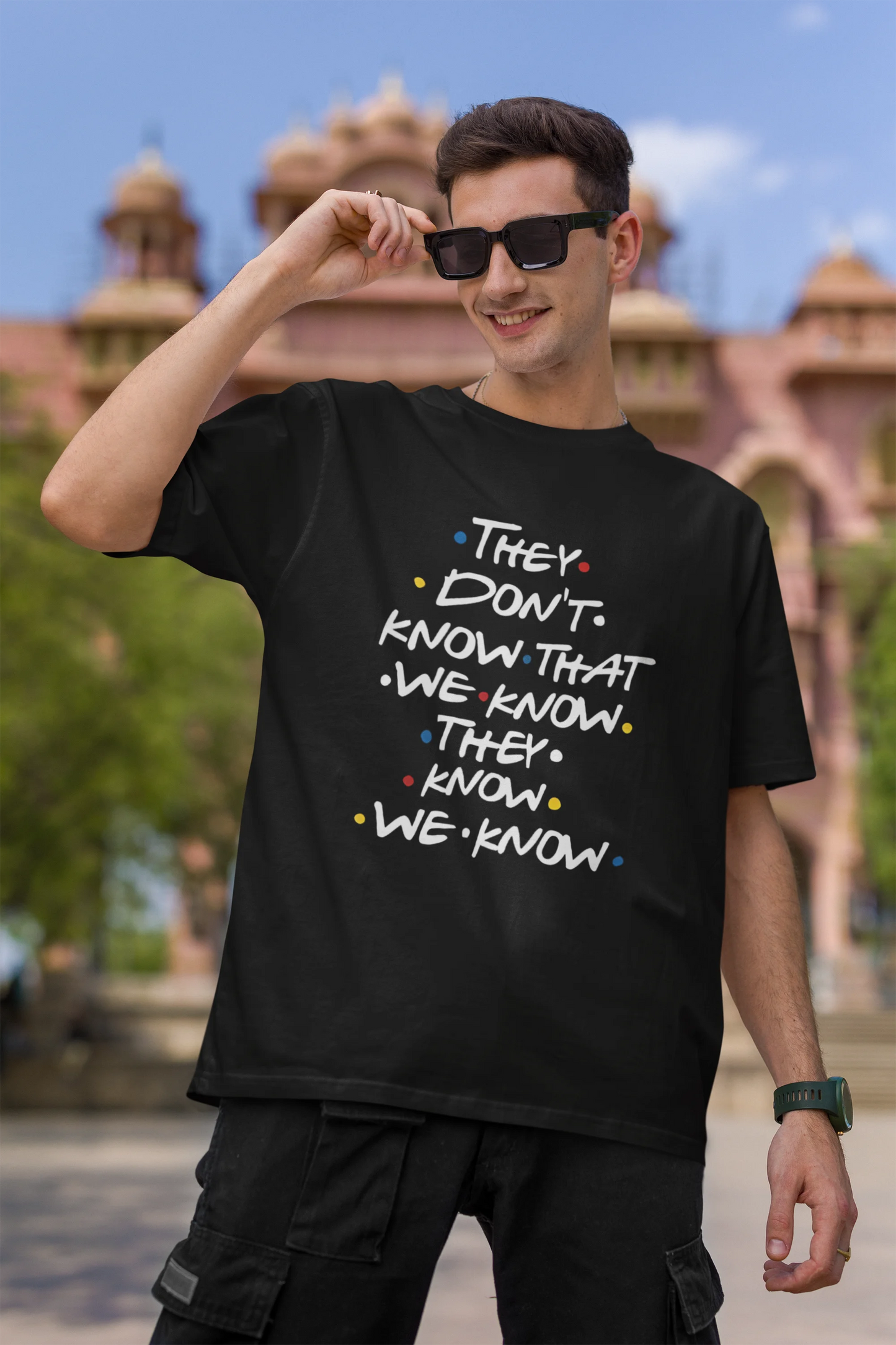 First image of male model wearing black oversized t-shirt with F.R.I.E.N.D.S series inspired designs, embodying Phoebe's unique humor with the quote 'They Know We Know'