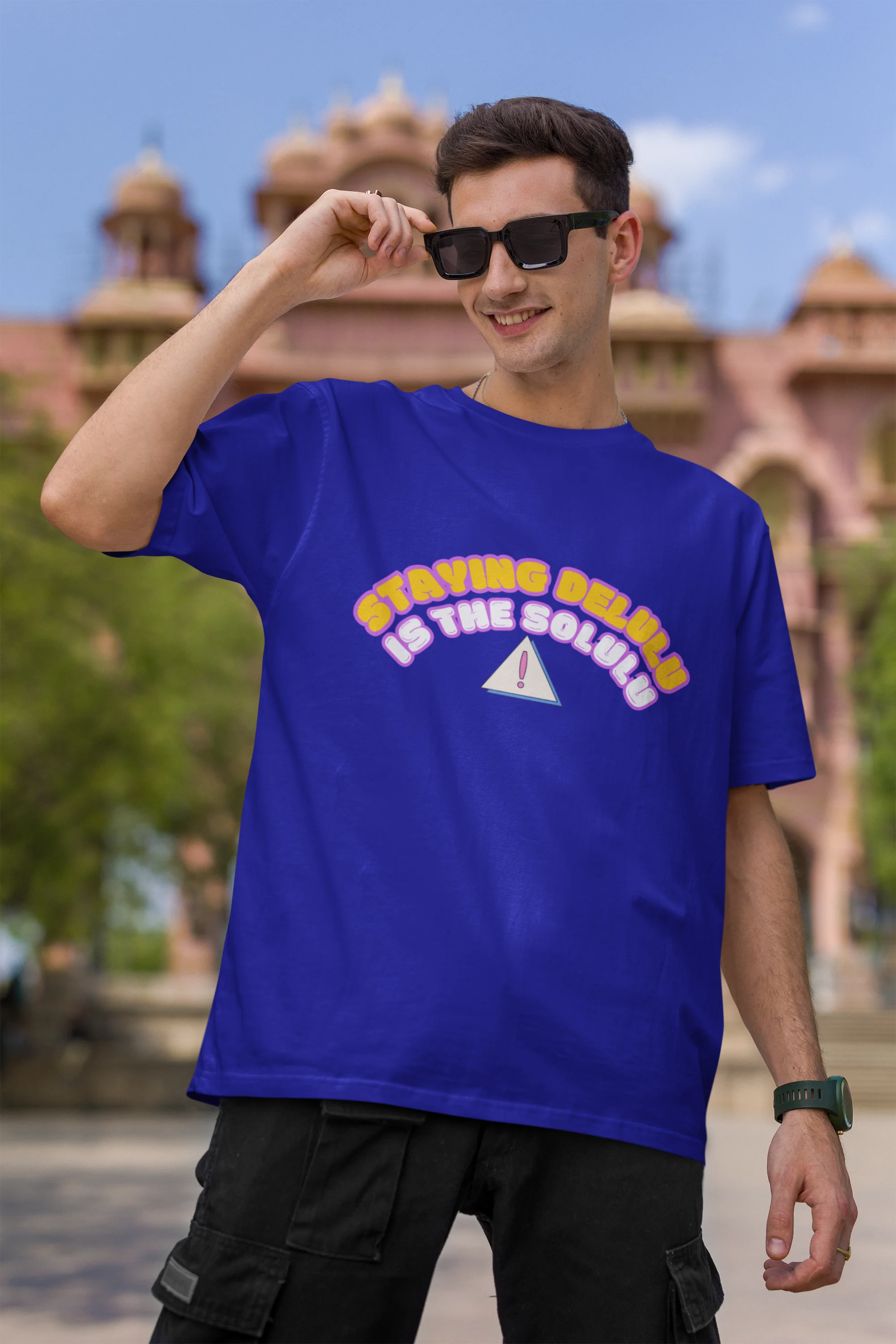 First front view male model wearing an royal blue oversized t-shirt with the hilarious message "Stay Delulu" in a bold design. Ideal for those who love trendy slang and lighthearted humor.