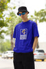 Left side view of a male model wearing a royal blue oversized t-shirt featuring a design inspired by Alessia Cara's song 