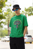 Left side view of a male model wearing a forest green oversized t-shirt featuring a psychedelic magic mushroom with an aura, perfect for a hippie, trance, or groovy style.