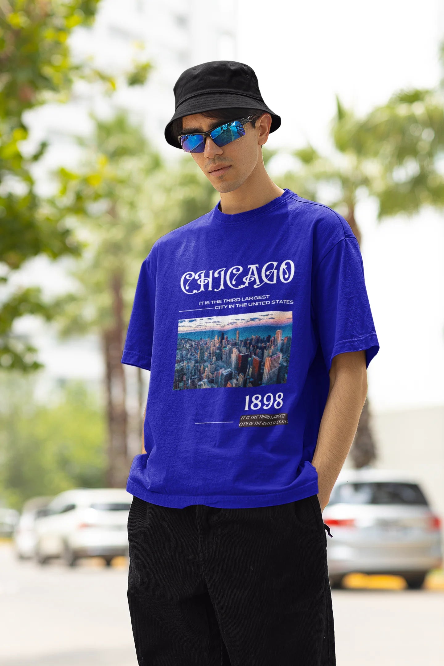 Right side view of male model wearing a royal blue oversized t-shirt with a Chicago skyline design, offering a relaxed urban aesthetic.
