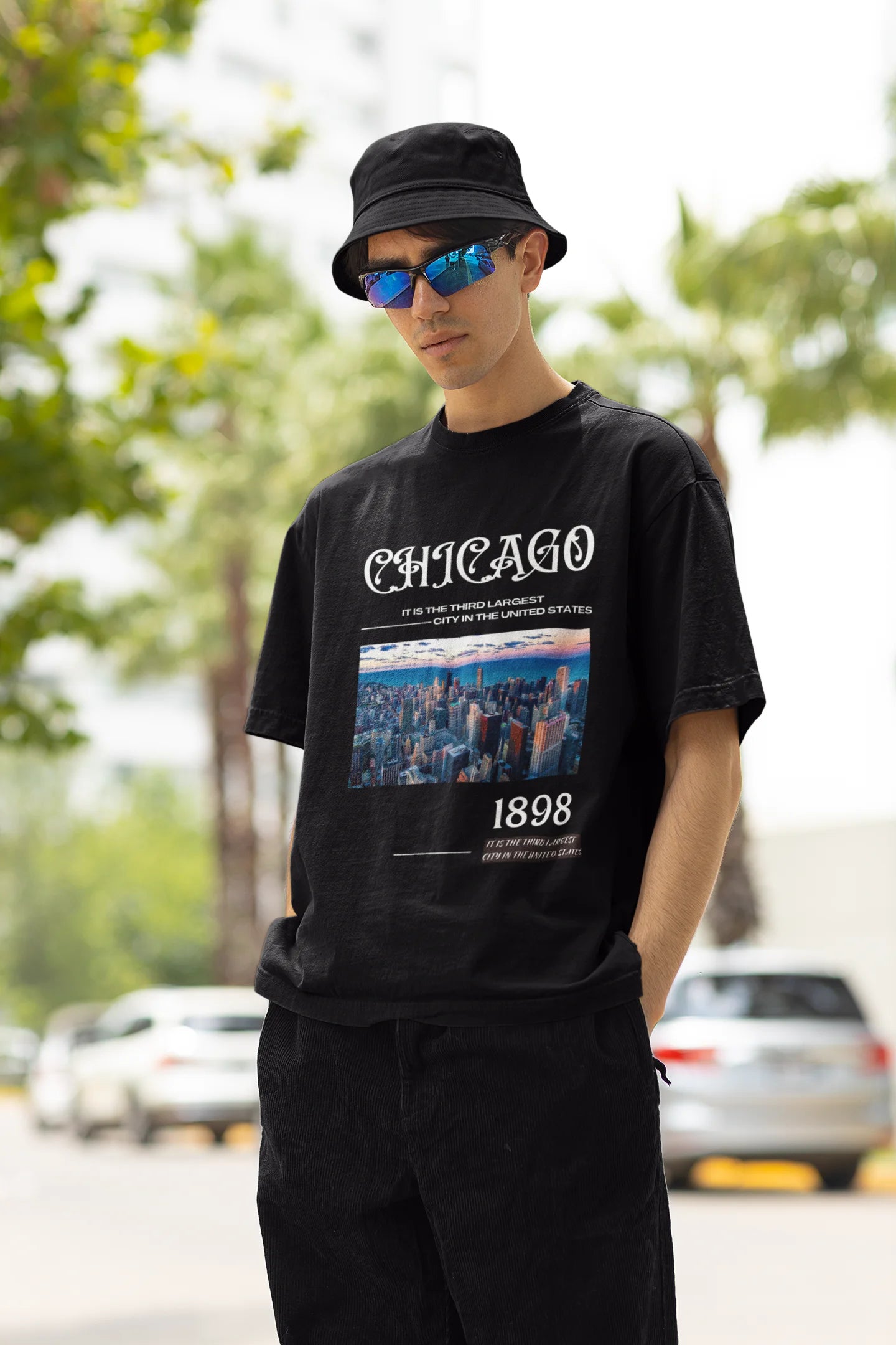 Right side view of male model wearing a black oversized t-shirt with a Chicago skyline design, offering a relaxed urban aesthetic.