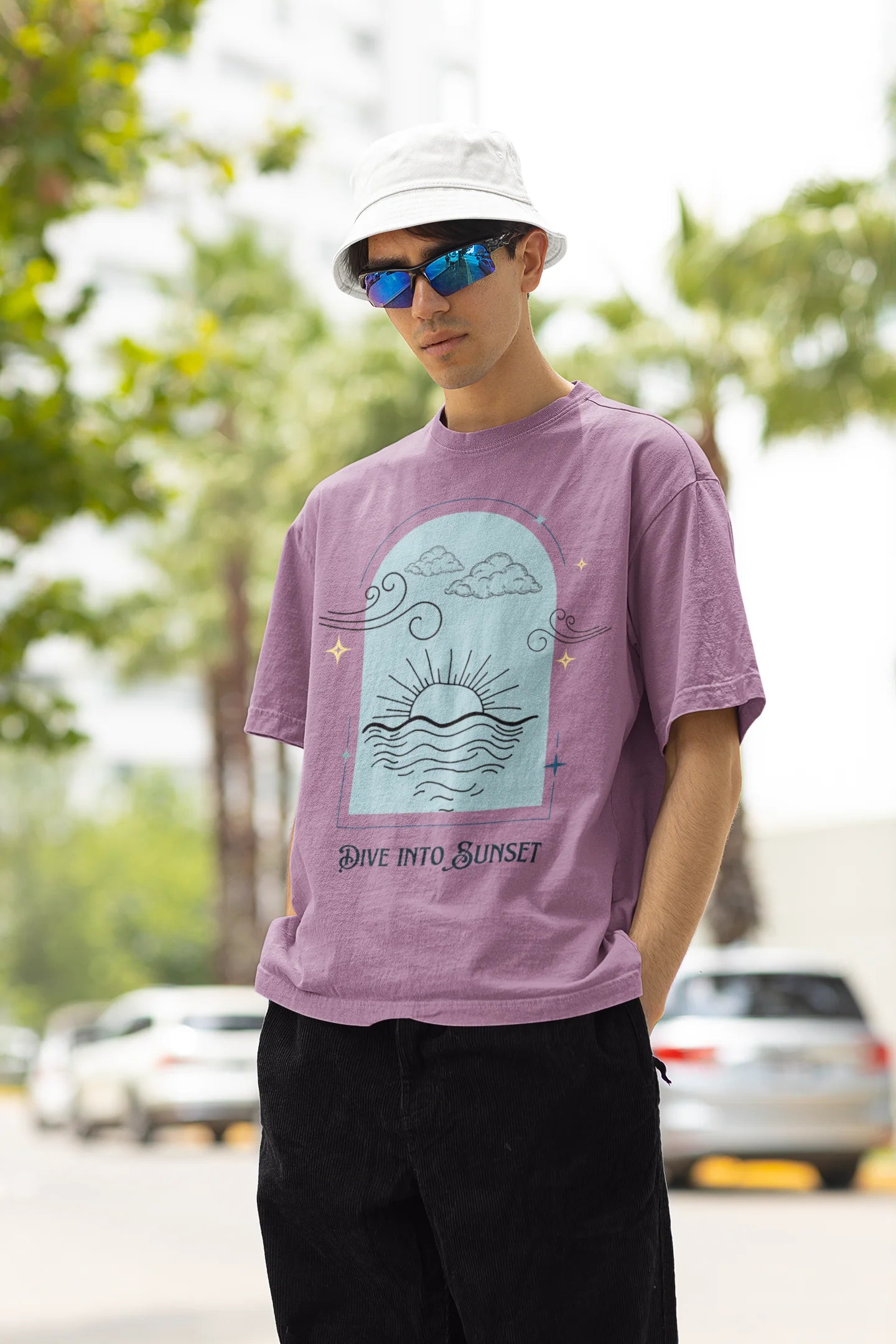 Left side view of a male model wearing a dirty purple oversized t-shirt with a beautiful outline of the sun setting into the sea, offering a serene and coastal aesthetic.