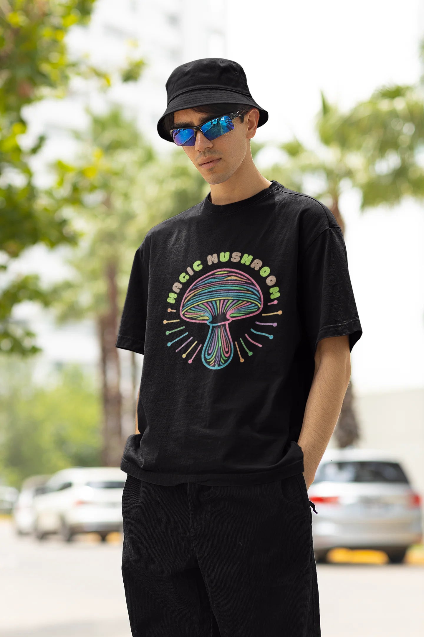 Left side view of a male model wearing a black oversized t-shirt featuring a psychedelic magic mushroom with an aura, perfect for a hippie, trance, or groovy style.