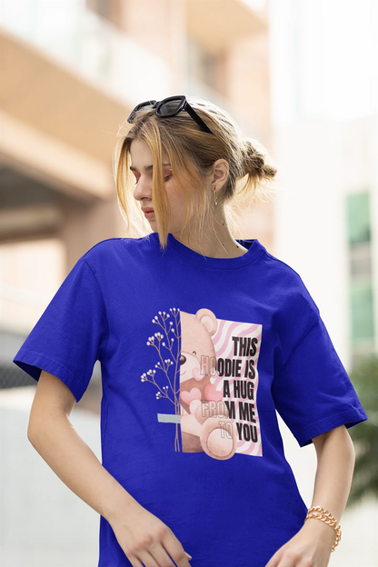 First front view of a female model wearing an royal blue oversized t-shirt with a heartwarming design of a teddy bear offering a hug, offering a comforting and relaxing aesthetic.
