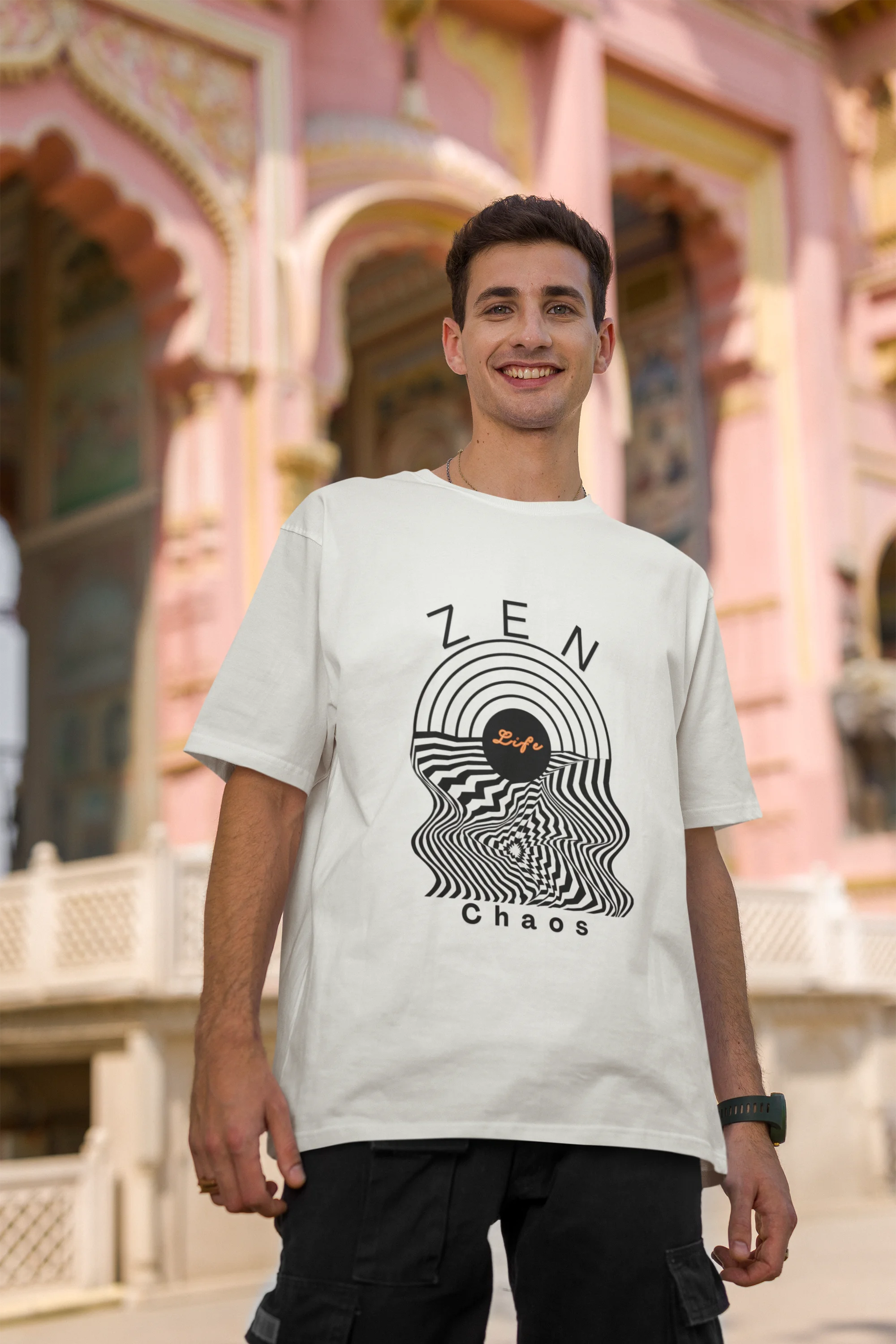 Second front image of a male model wearing an off-white oversized t-shirt featuring an aesthetic design of a setting sun and crashing waves with the text "Zen & Chaos" above it. Ideal for those who love philosophical themes and visually striking clothing.