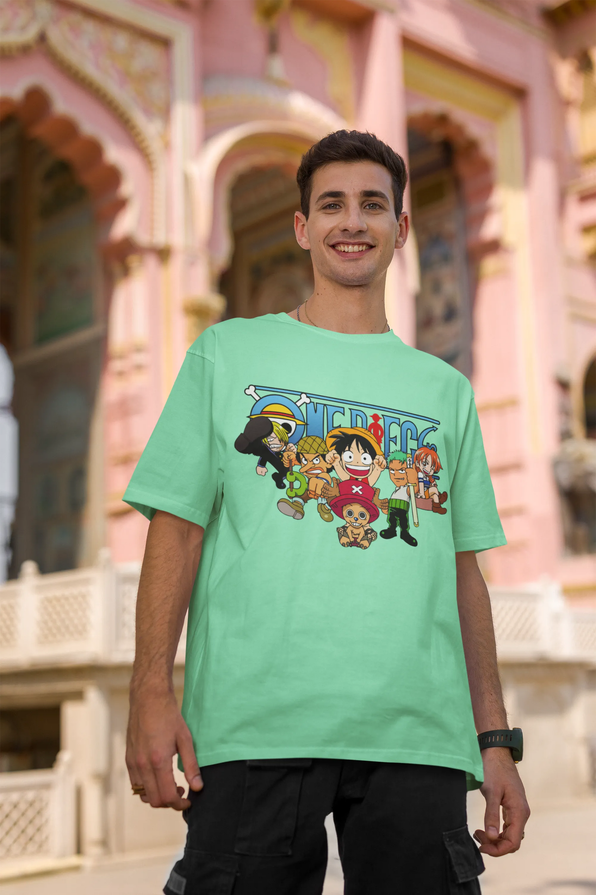 2nd front view of a male model wearing a mint green oversized t-shirt featuring chibi versions of the Straw Hat Crew from the One Piece anime.