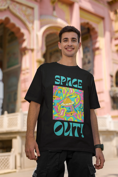 First image of male model wearing an black oversized "Spaced Out" t-shirt featuring a vibrant color mashup design that evokes a sense of space exploration, playful aliens, and distant galaxies.