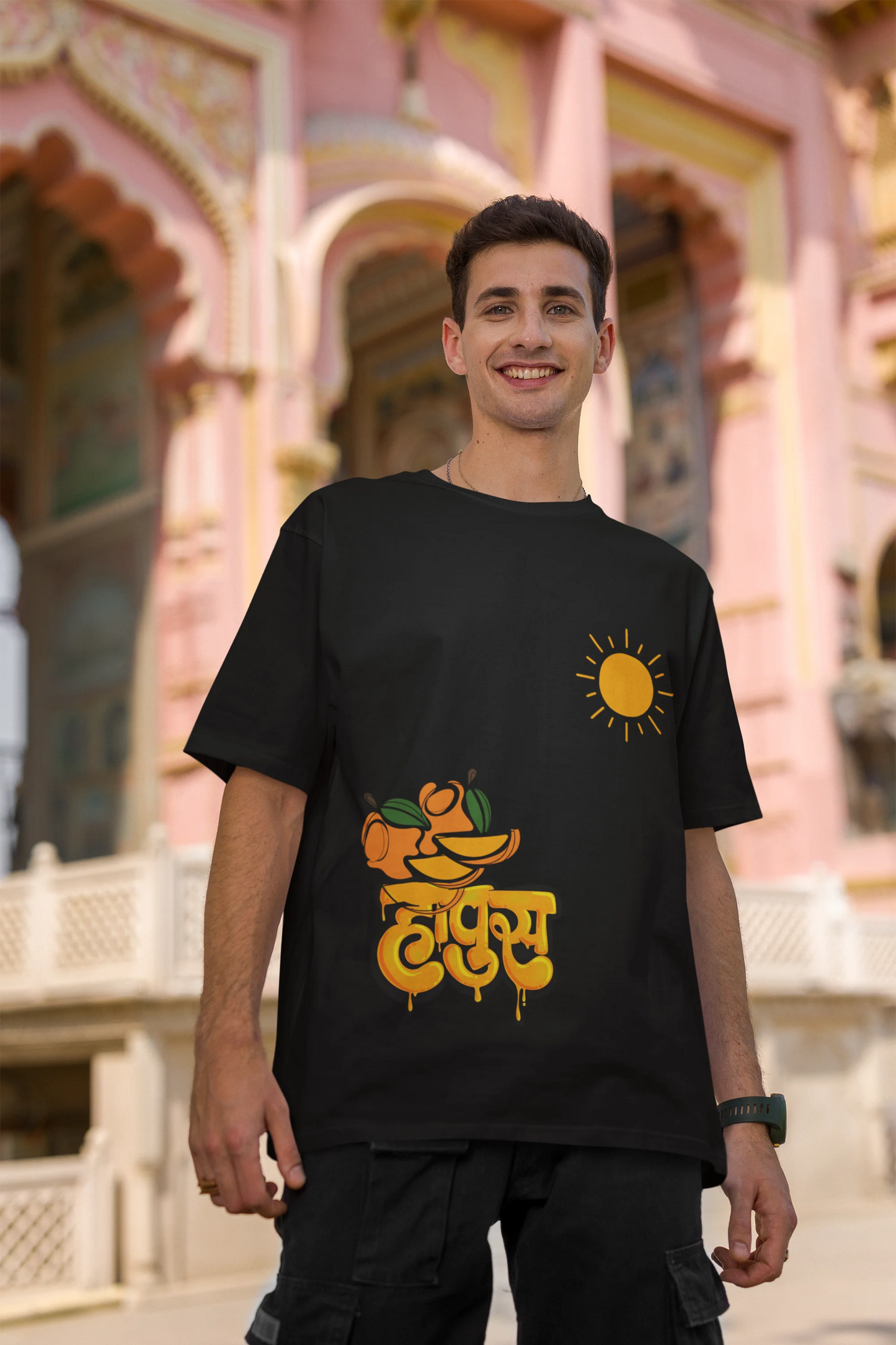 Third front view of male model wearing an black oversized t-shirt featuring a design inspired by the Marathi word "Hapus," meaning Alphonso mango. Ideal for fans of Marathi culture, foodies, and anyone who loves the king of fruits.