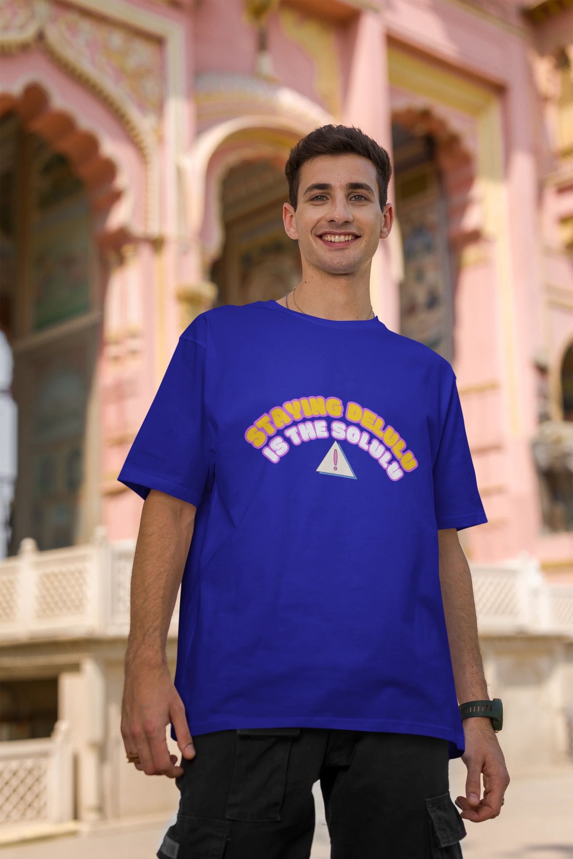 Second front view male model wearing an royal blue oversized t-shirt with the hilarious message "Stay Delulu" in a bold design. Ideal for those who love trendy slang and lighthearted humor.