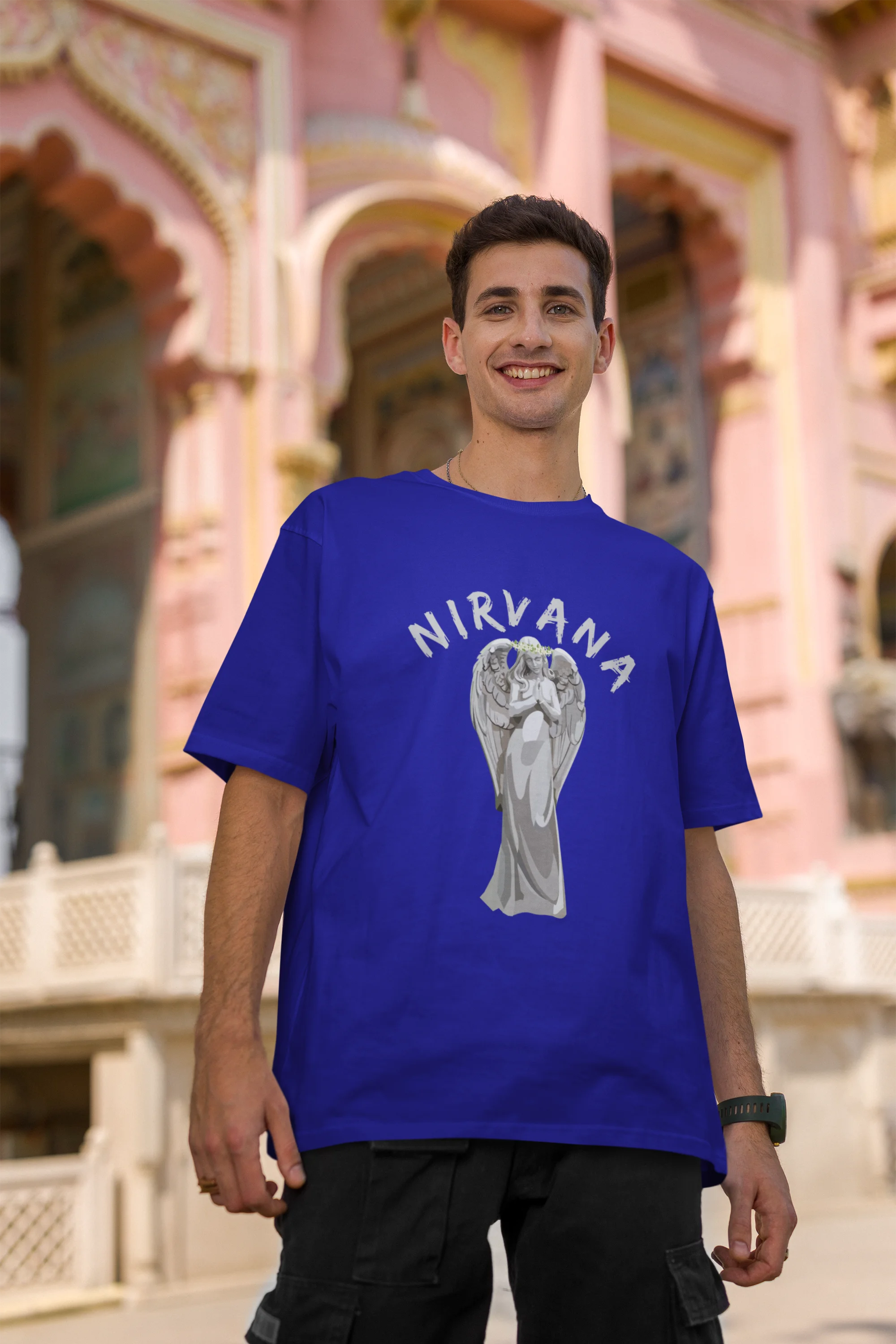 Second front image of male model wearing a\ royal blue oversized t-shirt featuring a design of a winged angel with the text "Nirvana" above it. Ideal for fans of Nirvana and those who love grunge aesthetics.